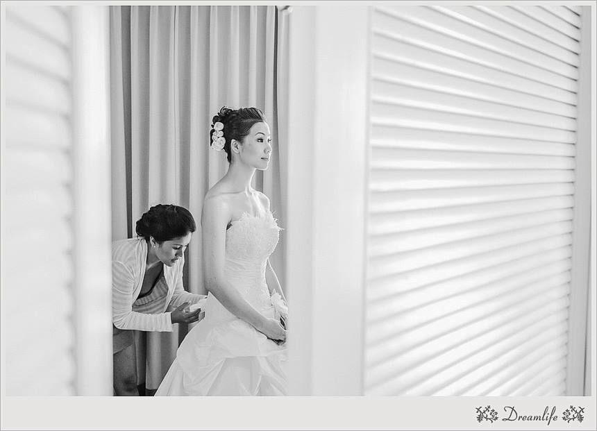 Black and white photo of Angela getting final adjustments made to her wedding dress