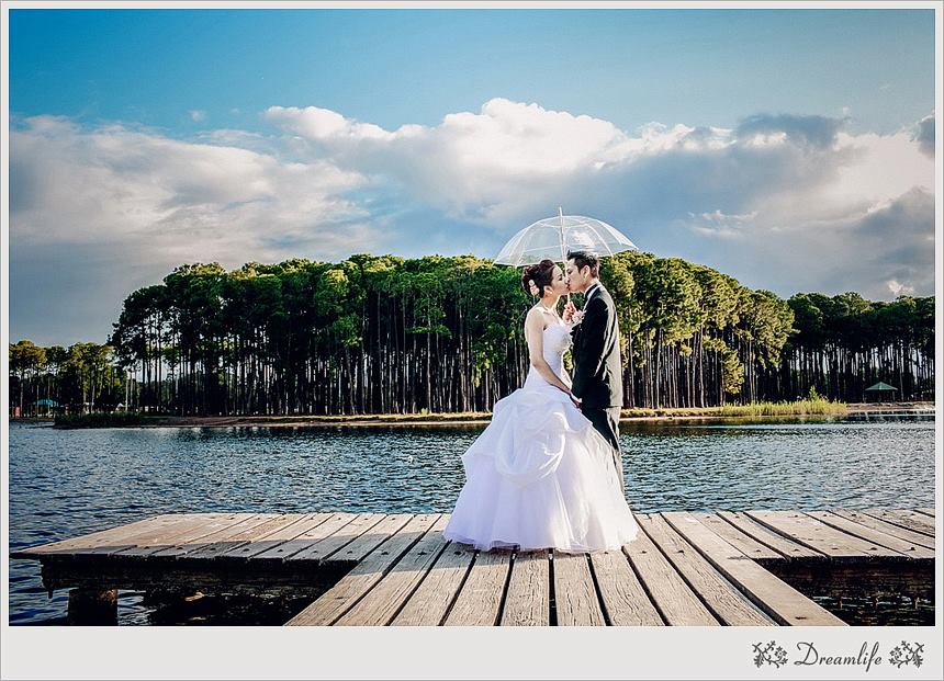 Amanda and Martin under umbrella for wedding photo on lake jetty