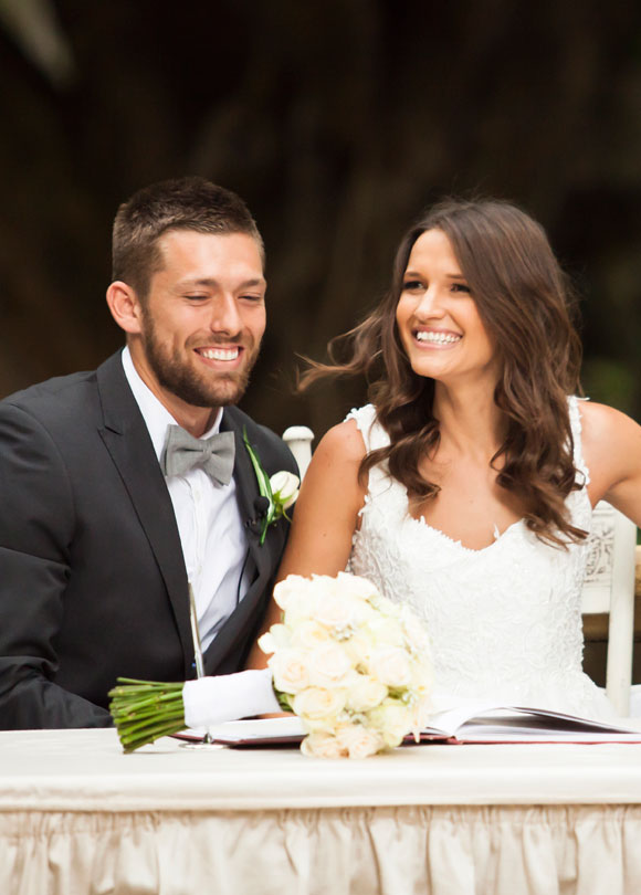 Bride and groom smiling sitting at table outside