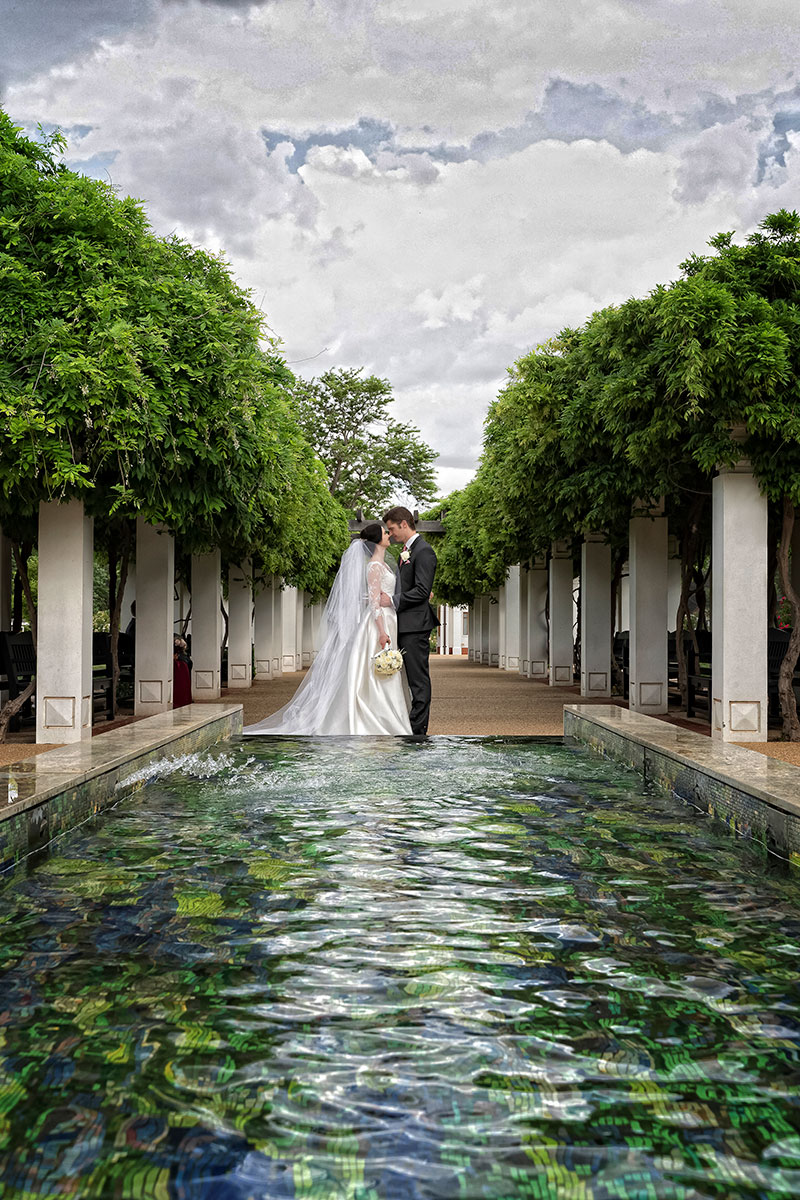 Bride and Groom in front of a water feature with columns on both sides.