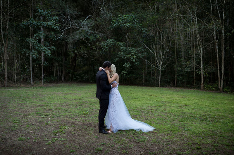 Photo taken by Leigh Warner Weddings of Bride and Groom in clearing in front of rainforest setting.