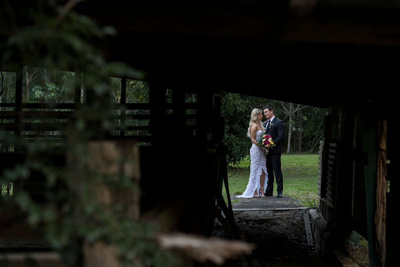 Photo taken by Leigh Warner Weddings of Bride and Groom framed by a shed in the foreground.