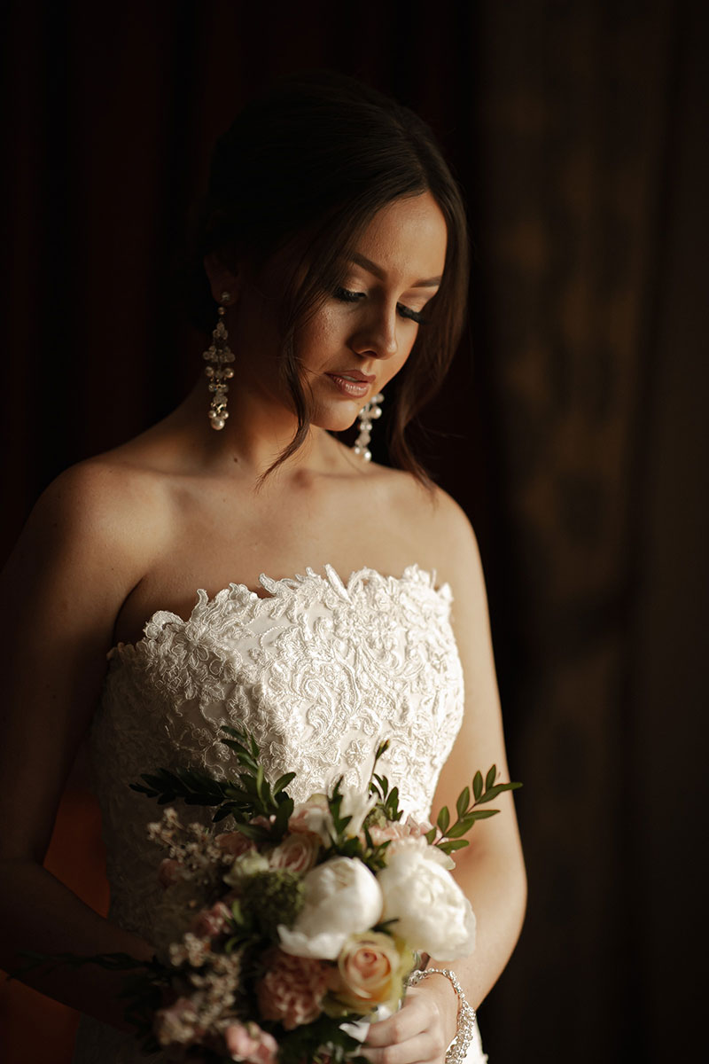 Photo by Tom Judson Photography of Bride holding flowers and looking pensive.