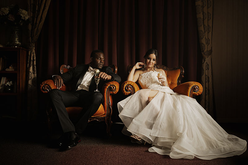 Photo by Tom Judson Photography of Bride and Groom relaxing with champagne on ornate chairs.