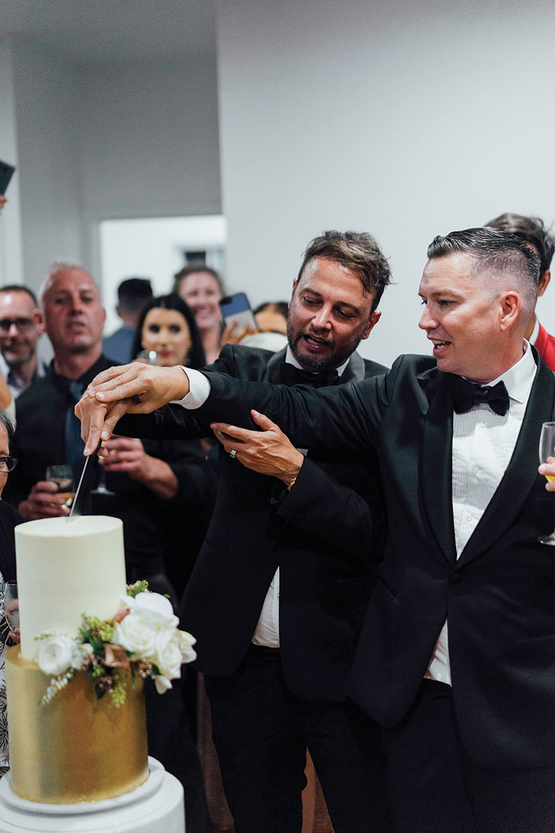Brad and Scott with their guests, cutting their wedding cake.