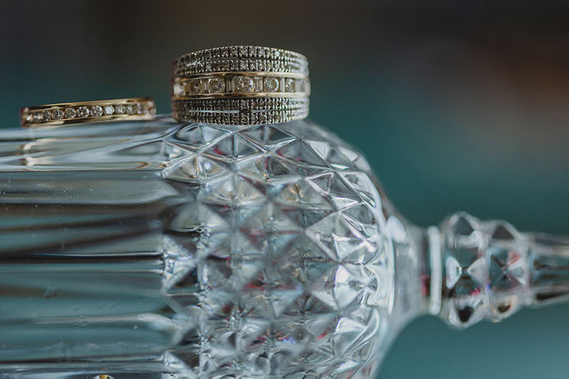 Crystal bottle with wedding rings on top.