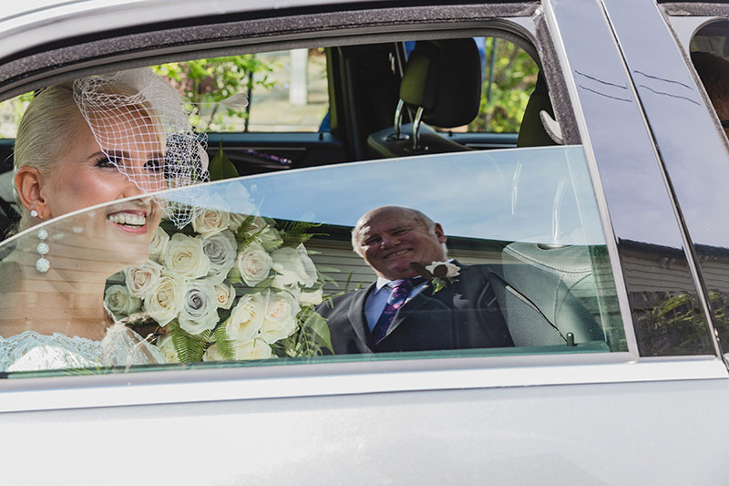 Smiling bride arrives at Broadway Chapel in a Mercedes Benz.