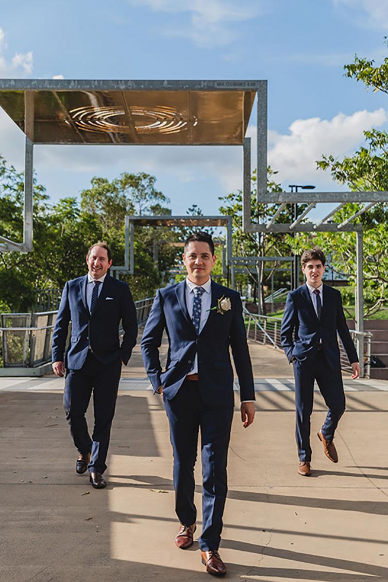 Groom and his two groomsmen in their dark blue suits.