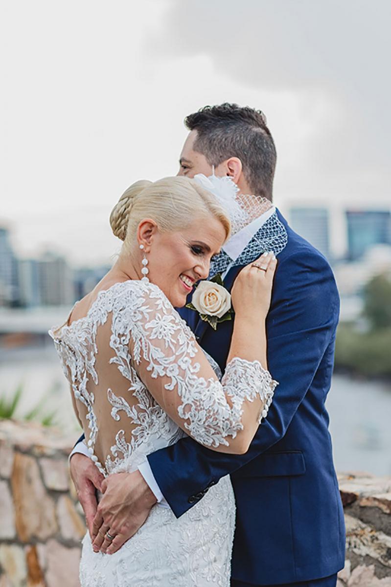 Bride and groom hugging with Brisbane city in the background..