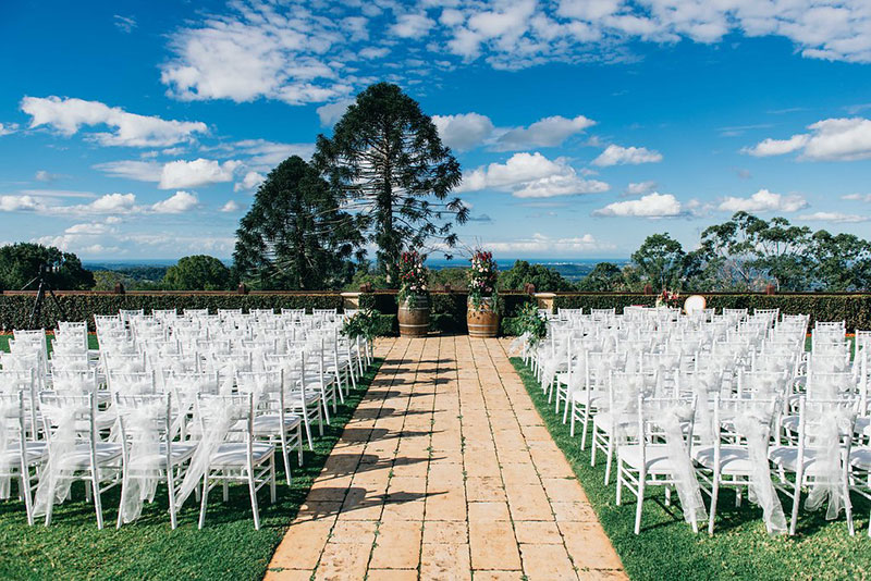 Outside wedding ceremony with white chairs at Flaxton Gardens.