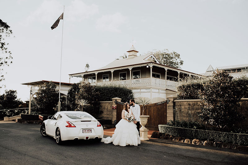Bride and groom with wedding car outside Flaxton Gardens.