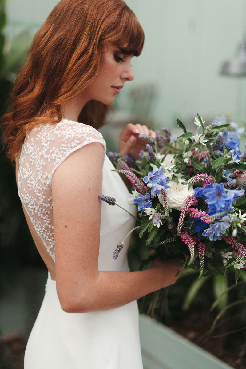 Bride with flowers in sleek gown.