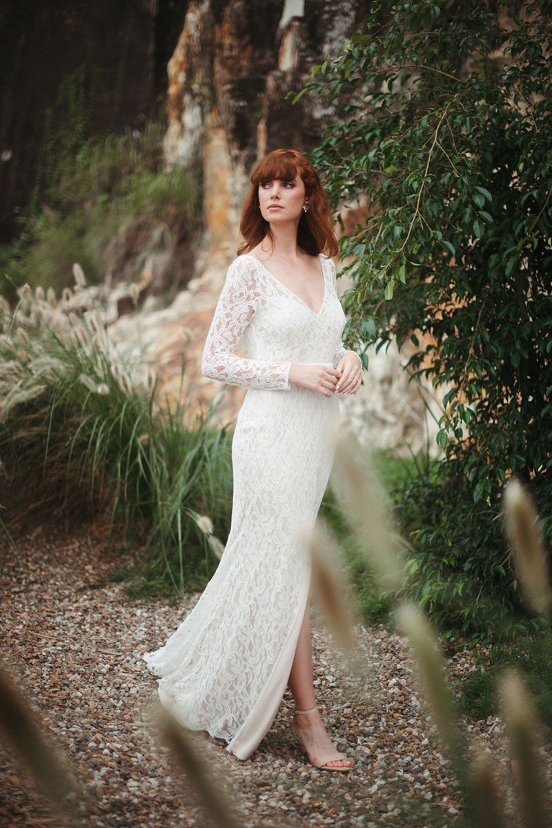 Lace gown worn by red haired bride in outdoor setting.