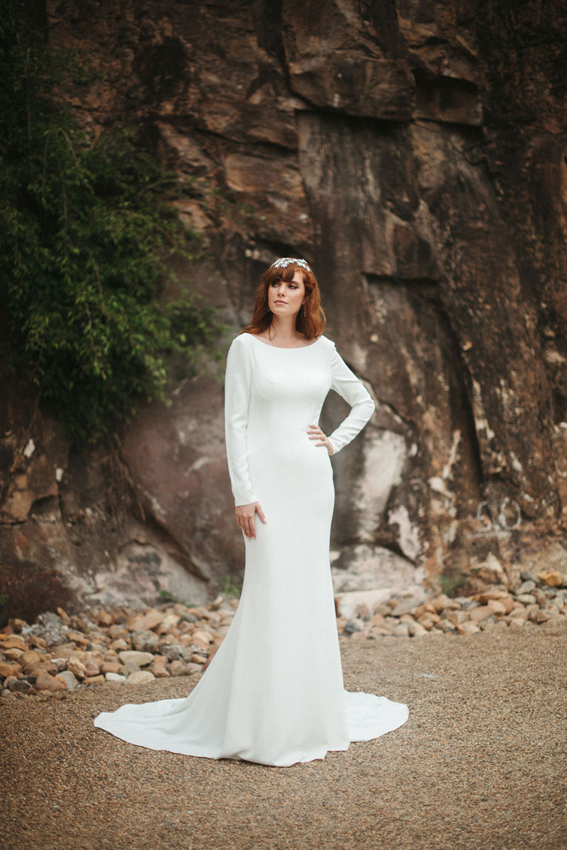 Bride in outside setting wearing a long sleeved wedding gown.