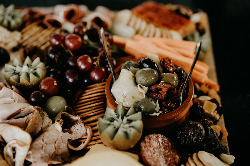 Close up of a grazing board with antipasta, kiwi fruit and more.