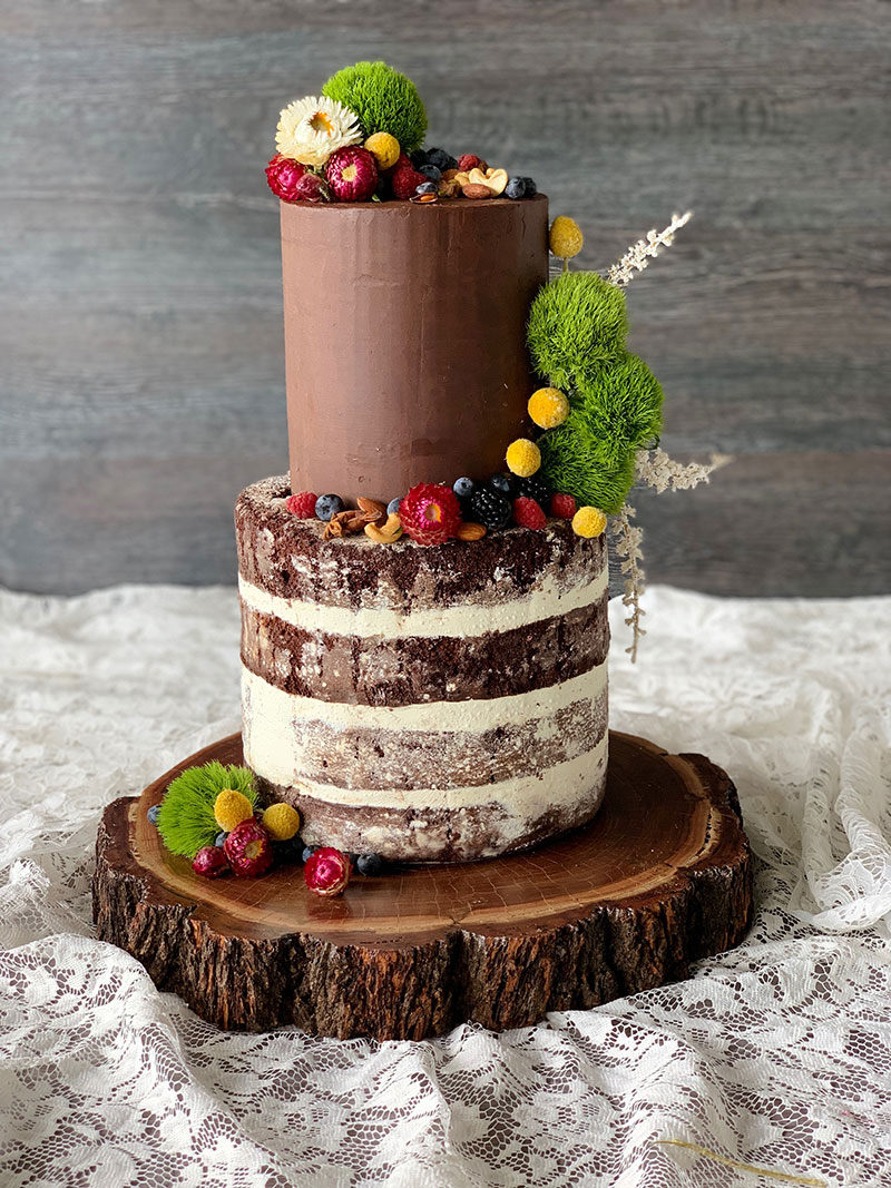 Rustic wedding cake with fruits, nuts and greenery.