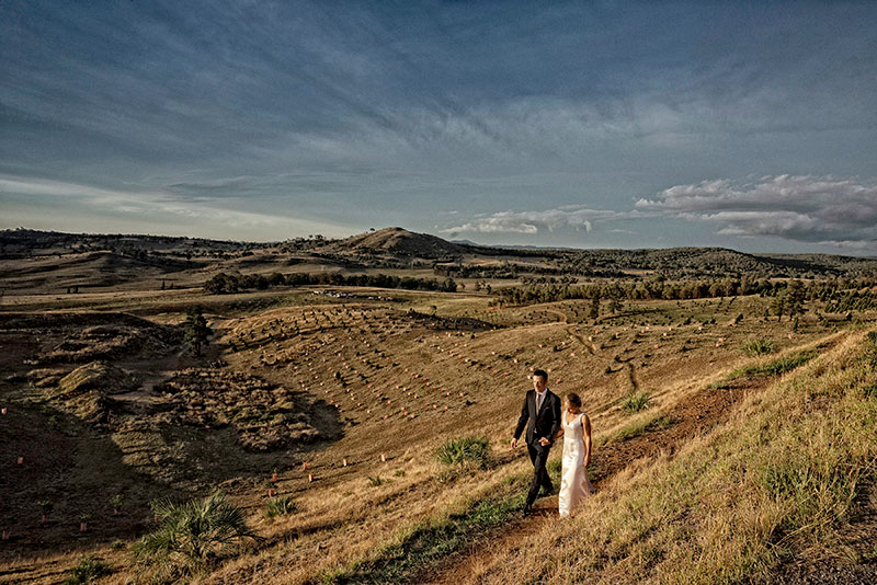 Bride and Groom walking on a track surrounded by rural country landscape.