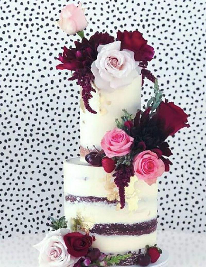 Rustic wedding cake with striking deep red florals.