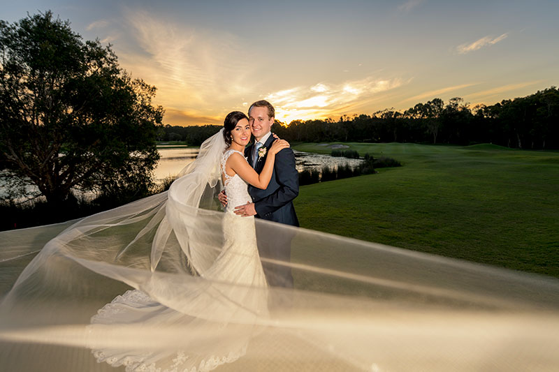 Bride and groom hold each other with a sunset on Twin Waters Golf Club.