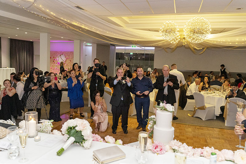 Guests and Photographer trying to take photos of couple at their wedding reception.