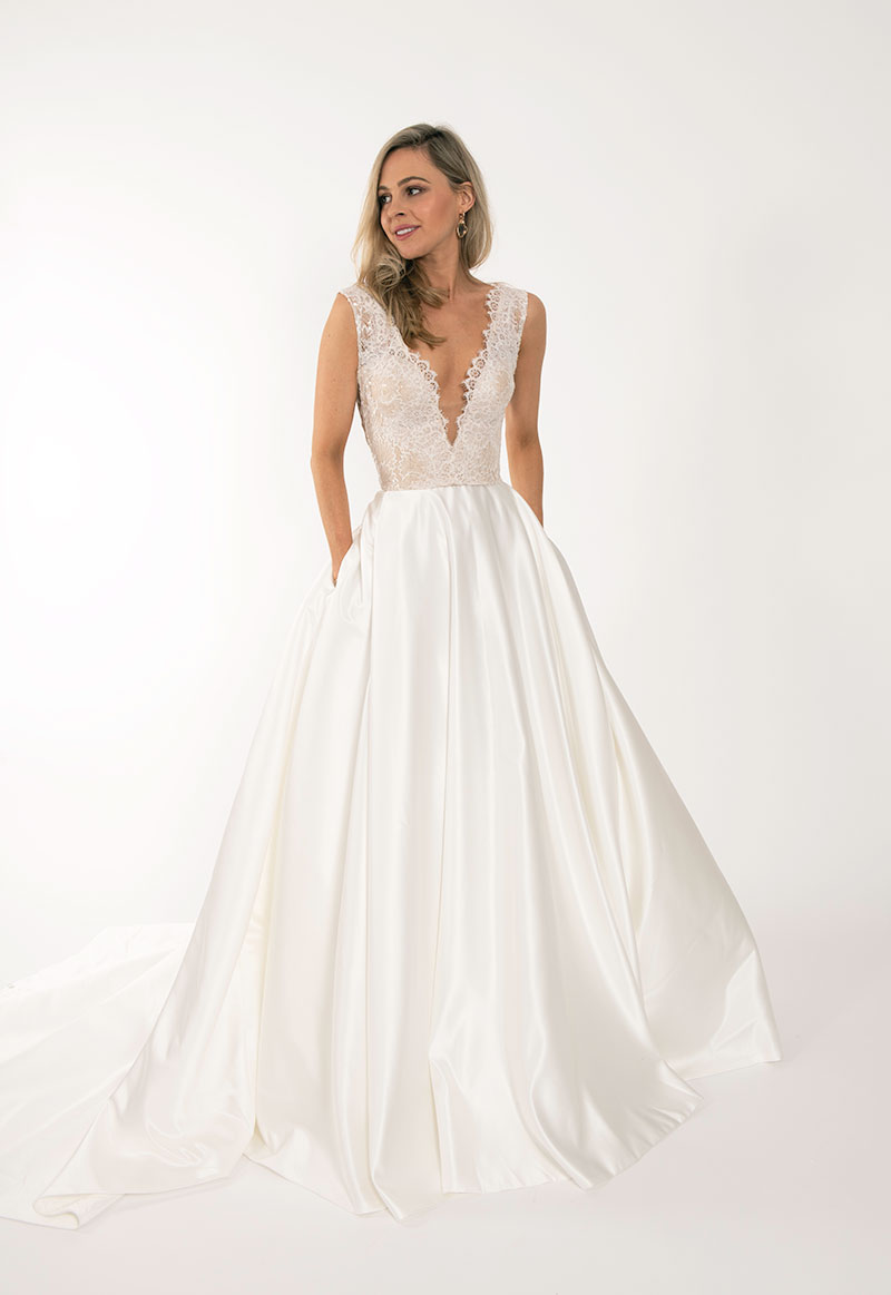 Low-cut fitted bridal bodice with flowing skirt by Q'Nique Exquisite Bridal Wear.