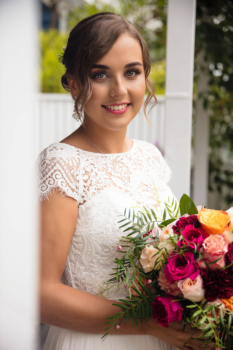 Bride smiling holding big bouquet of flowers.